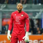 Maduka Okoye, Nigerian goalkeeper for Udinese Calcio, wearing the red number 40 goalkeeper kit with “IO SONO FRIULI VENEZIA GIULIA” and Banca 360 sponsors during a Serie A match.